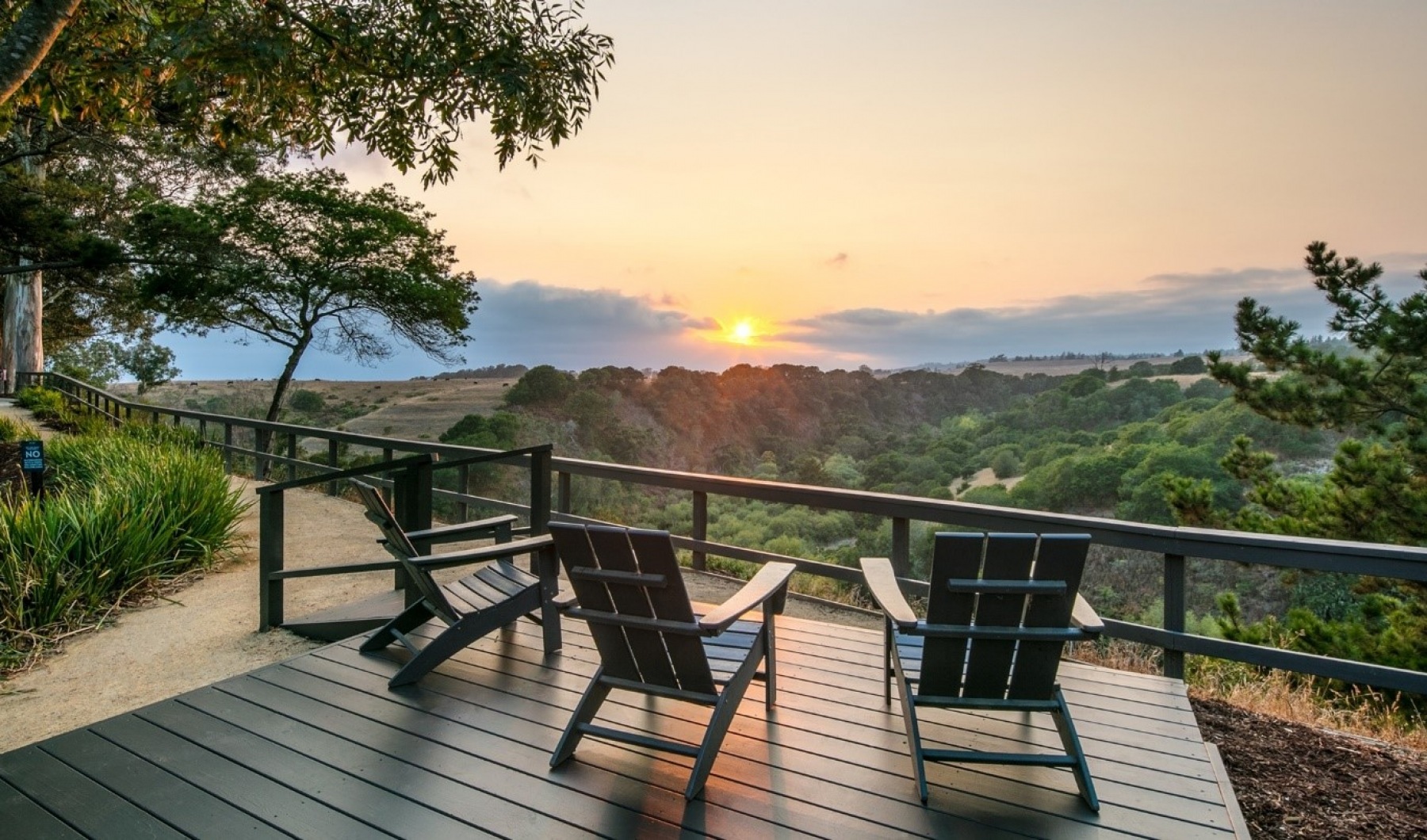 lifestyle image of chairs on a wooden patio overlooking a view